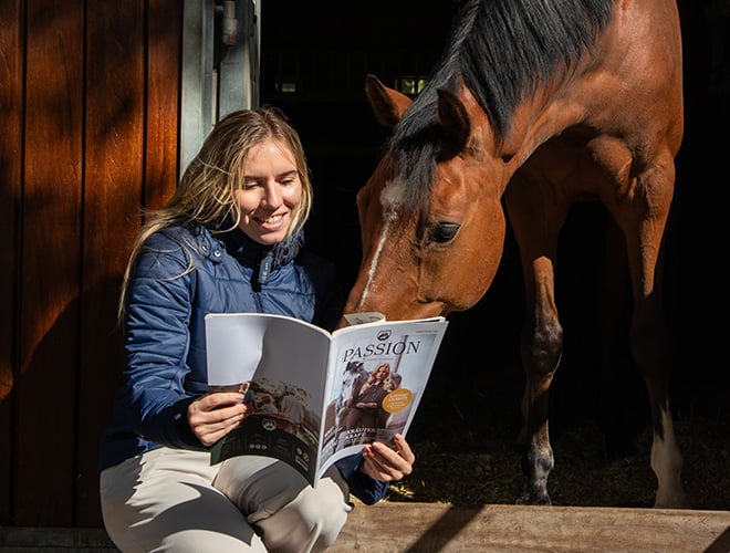 Eine Frau und ein Pferd lesen gemeinsam im Loesdau Passion Magazin